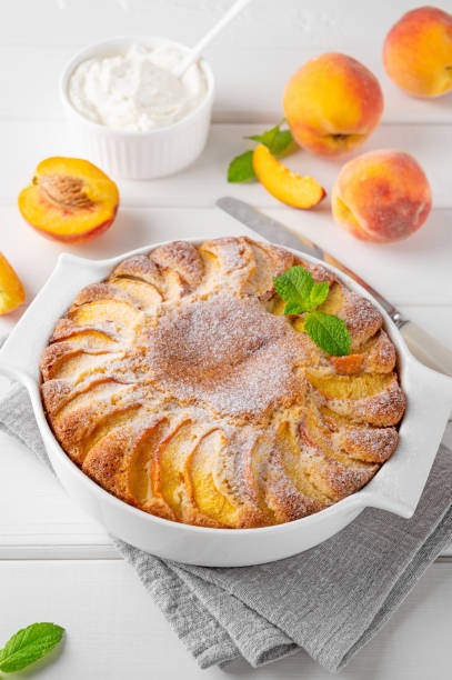 istock Delicious peach pie in a white ceramic baking form on a white wooden background. Summer cake. Selective focus, copy space. 2118784400