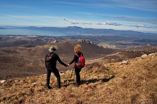 Rear view of mature couple hiking in the mountains and looking at the view