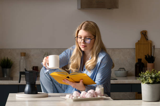 istock Woman reading book in morning kitchen scene 2118918954