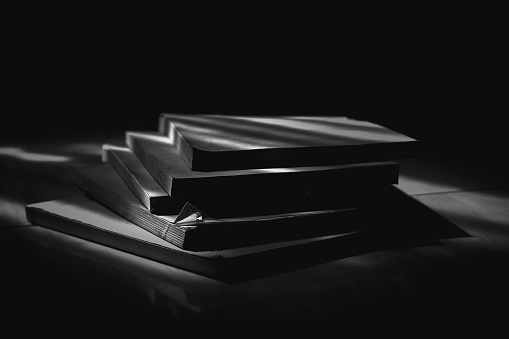 A pile of books exposed to light in a dark room
