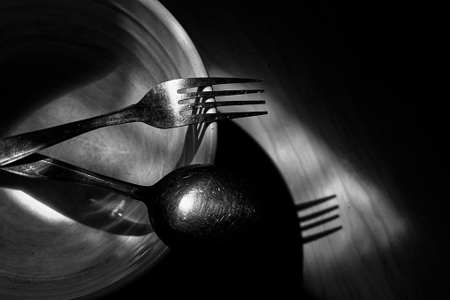Spoons and forks in bowls, tableware in low light