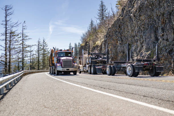 istock Two tree log carrier big rig semi trucks with semi trailers met on a mountain road moving towards each other 2118958127