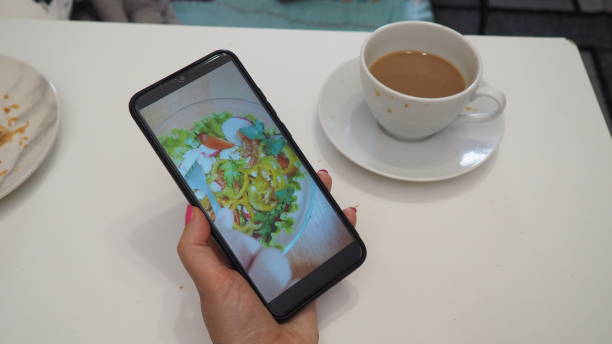 istock girl communicates on the phone with social networks, makes a post, scrolls the feed, makes an online order drinks coffee eating pastries. woman hands holding smart phone copy space green screen mockup 2118981604