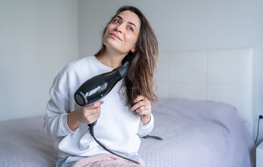 Woman Drying Her Hair With Hairdryer At Home