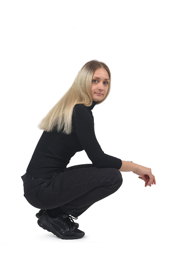 side view of a woaman sitting on her haunches looking at camera on white background