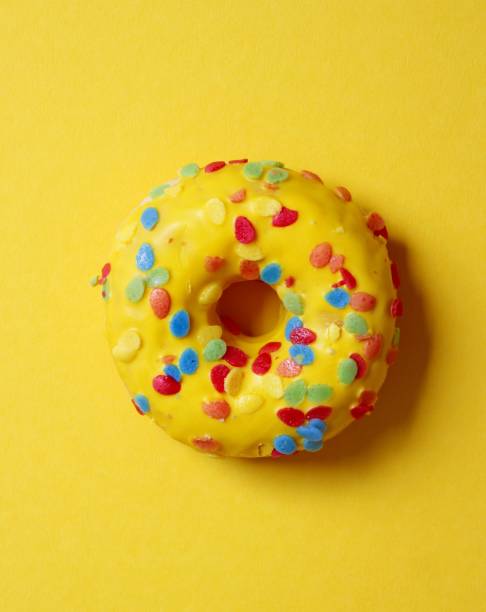 istock A yellow donut with chocolate icing and sprinkles against a yellow background, perfect for wallpaper 2119007992