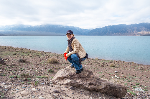 Blue lake and mountains. Travel scene, woman making a memorable funny photo. Bartogai reservoir, Almaty, Kazakhstan