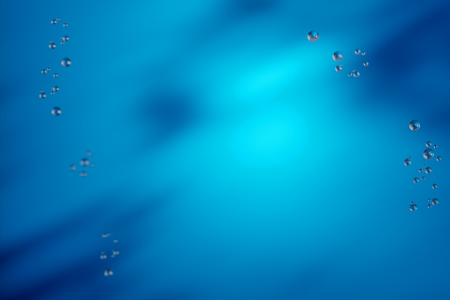 soft blue tones background. Sunbeams on water surface, bubbles. peaceful underwater view. Sunbeams pierce through water. Peaceful underwater environment