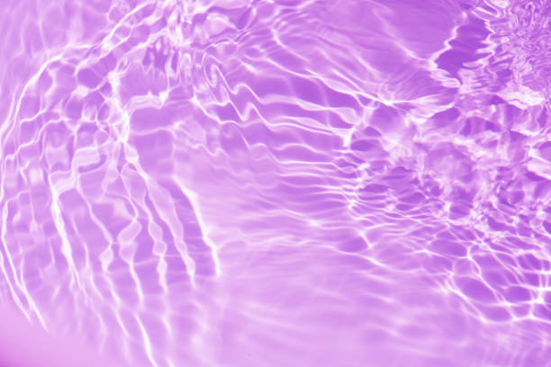 istock Purple water bubbles on the surface ripples. Defocus blurred transparent pink colored clear calm water surface texture with splash and bubbles. Water waves with shining pattern texture background 2119031549