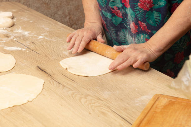 istock A woman rolls out the dough with a rolling pin on the table 2119049687