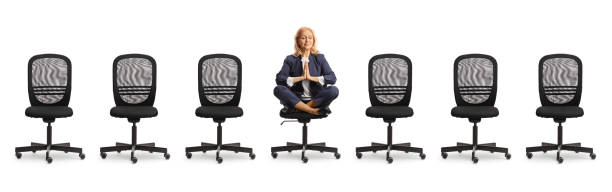 istock Businesswoman sitting and practicing yoga between empty chairs 2119054840