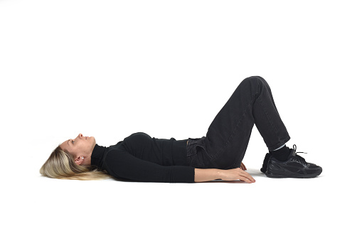 side view of a woman lying on the floor looking up on white background