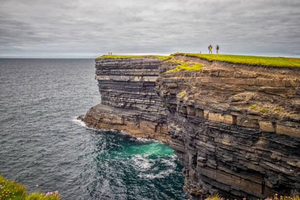 istock Cliff near Downpatrick Head - Two People Standing on Cliff Overlooking Ocean 2119101690