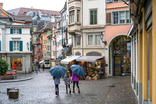 Family explores old town under umbrellas on a rainy day