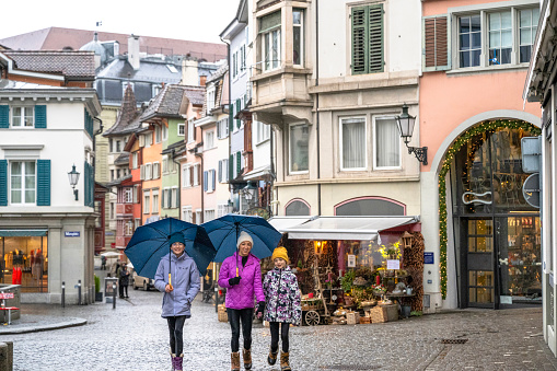 Family explores old town under umbrellas on a rainy day