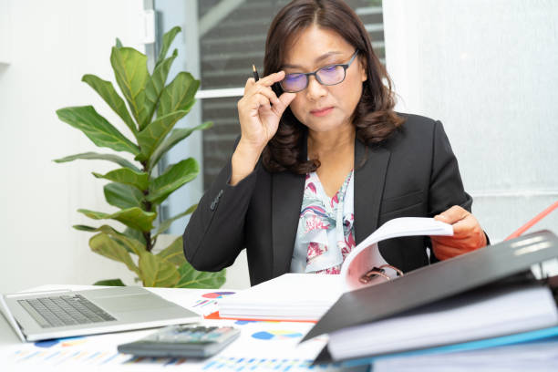 istock Asian accountant working and analyzing financial reports project accounting with chart graph and calculator in modern office, finance and business concept. 2119134263