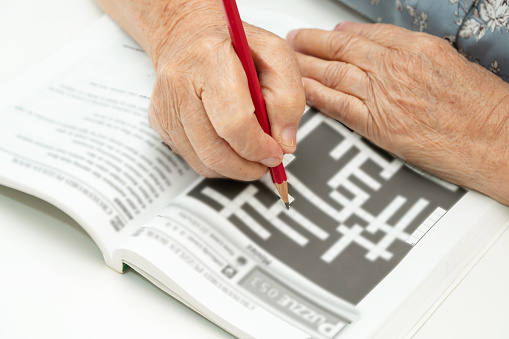Alzheimer disease AD, Asian elderly woman playing sudoku puzzle game to practice for dementia prevention.