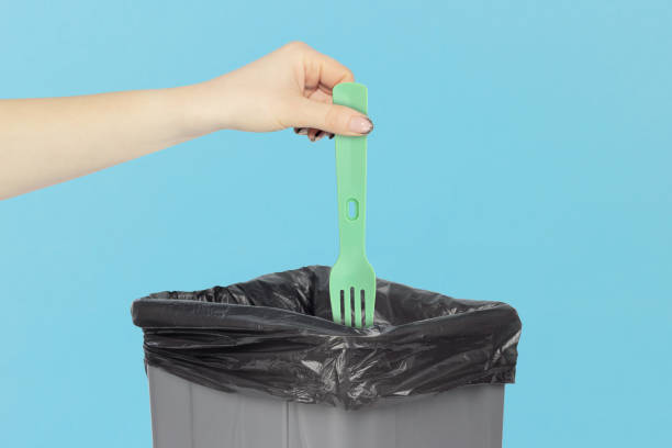 istock throw a plastic fork into the trash, disposable fork in hand in front of a trash can, plastic recycling concept 2119140050