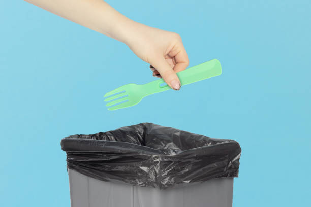 istock throw a plastic fork into the trash, disposable fork in hand in front of a trash can, plastic recycling concept 2119140051