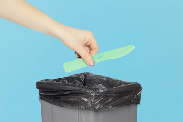 istock throw a plastic knife into the trash, disposable knife in hand in front of a trash can, plastic recycling concept 2119140052