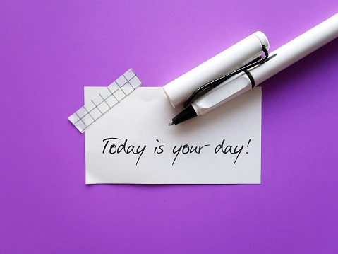 White note on purple background with handwriting - TODAY IS YOUR DAY - positive self talk affirmation for self motivation at work