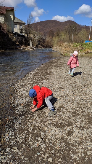 A boy and a girl are playing near a mountain river, twins. Photo.
