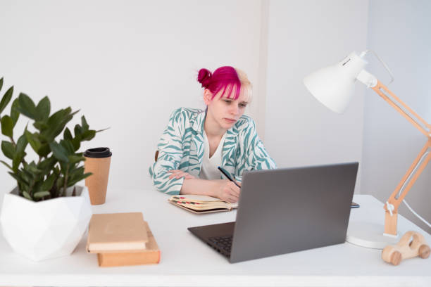 istock Young pink haired blonde woman sitting at table and working 2119227788
