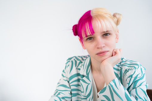 face portrait of young blonde woman with pink hair with white background