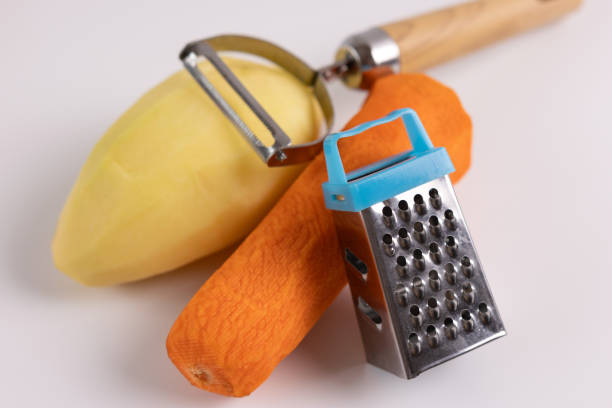 raw carrots, potatoes, skinning knife and grater on a white background. - raw potato red human skin farm стоковые фото и изображения