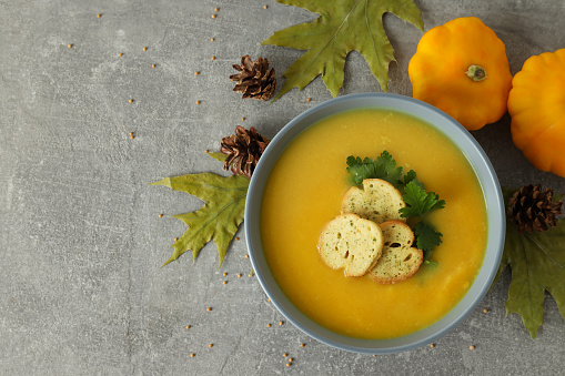 Concept of tasty food with pumpkin soup on gray textured table