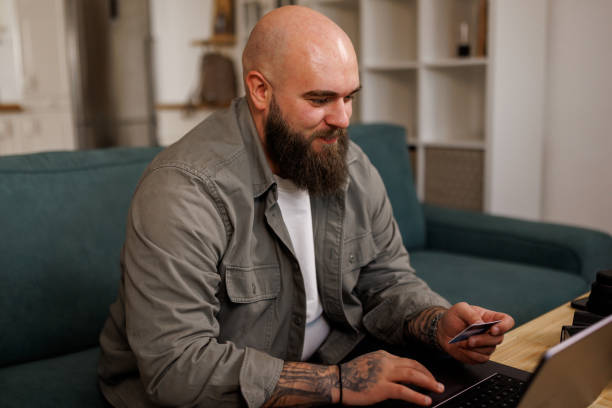 istock Young man using a laptop and credit card at home 2119273708