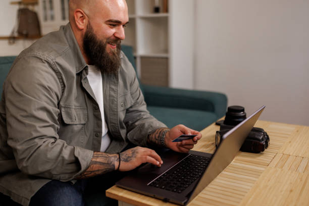 istock Young man using a laptop and credit card at home 2119273709