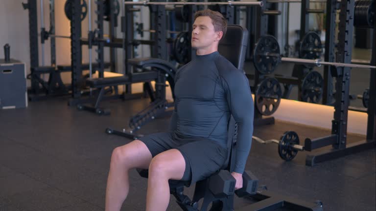 Fit athletic man doing dumbbell hammer curls at gym in slow motion