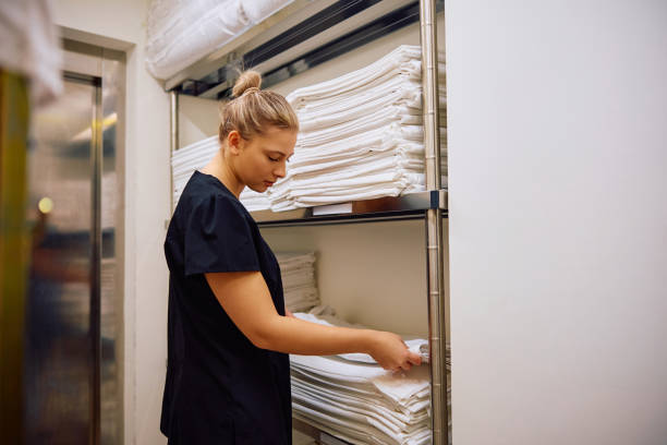 istock Young hotel maid taking bed sheets from laundry room. 2119344944