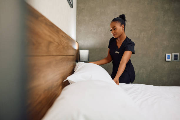 istock Young black hotel maid making bed in guest room. 2119365000