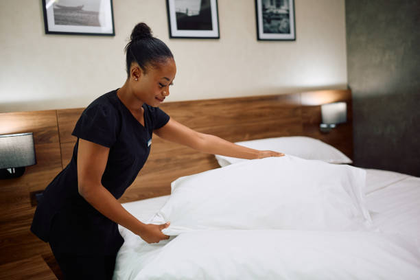 istock Smiling black maid changing bedding in hotel room. 2119367060