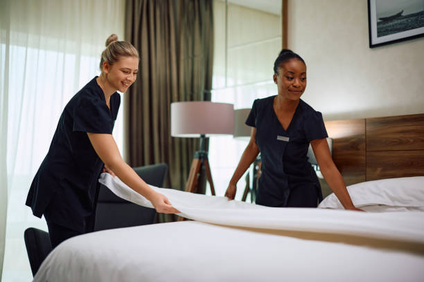 istock Young happy housekeepers making bed in hotel room. 2119369643