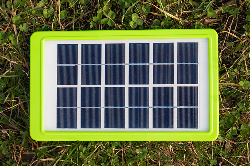 Portable solar panel on green border lying on grass, symbolizing mobile renewable energy solutions.