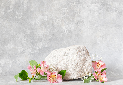 Podium texture stone for presentation and alstroemeria flowers on a gray texture background. still life. Copy space.