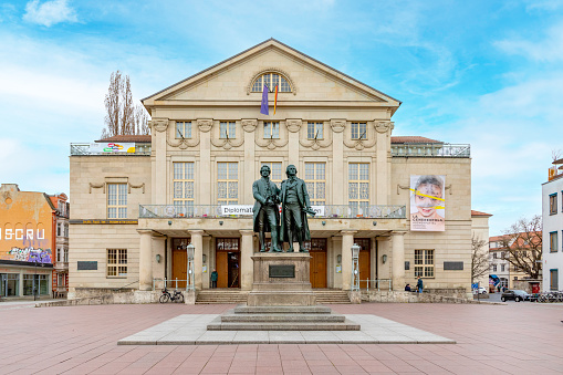 Weimar, Germany - March 18, 2024: Classic view of famous Deutsches Nationaltheater with Goethe-Schiller monument on a beautiful sunny day with blue sky in Weimar, Thuringia, Germany