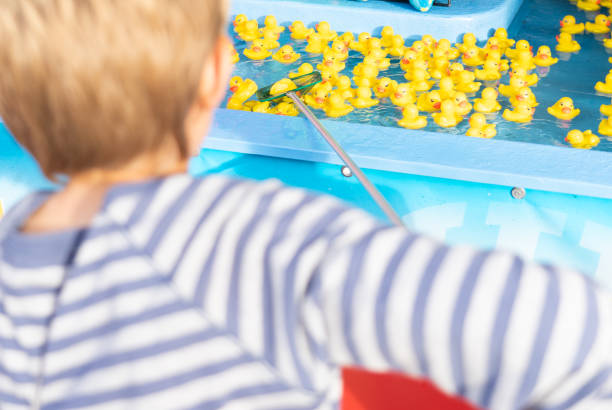 istock Boy fishing for rubber ducks with a net at a fair 2119384168