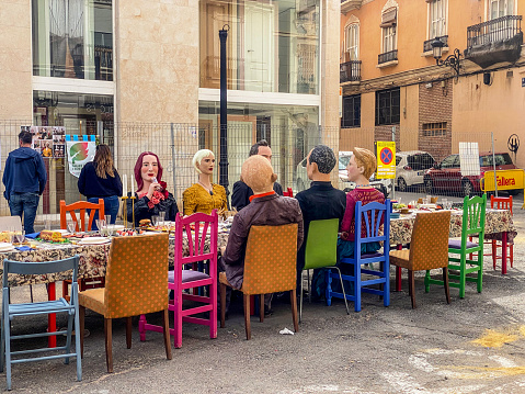 Valencia, Spain - March 19, 2024: Table in the middle of a street with ninots sitting around it. This are huge dolls that are built specifically to be burnt during the last night of Las Fallas annual event, exclusive to the Valencian Community