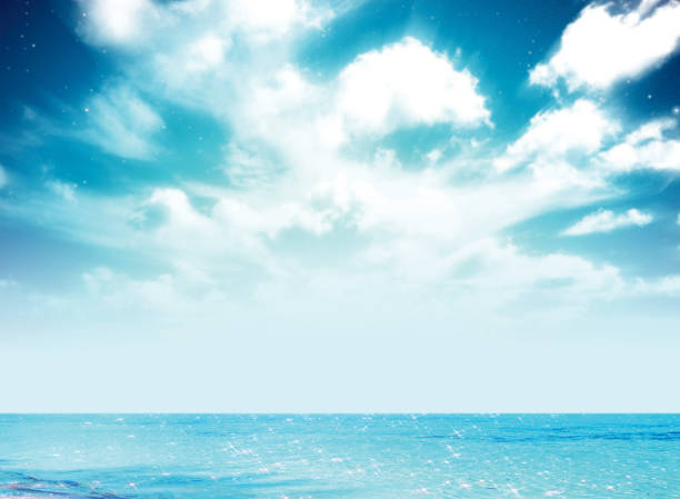 Blue sea surface with ripples and clouds on sky background