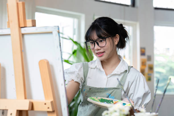 istock An artistic girl paints with acrylic paints on canvas with determination. 2119455943