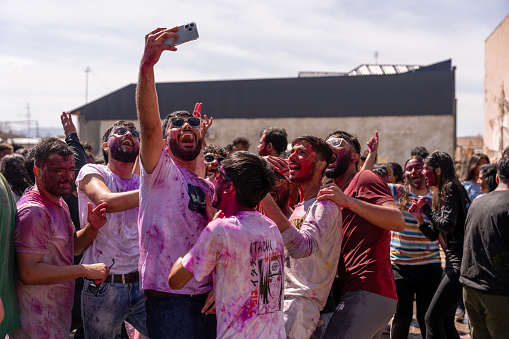 Uzbekistan, Samarkand, March 25, 2024: A group of people are celebrating and taking pictures with their cell phones. Scene is joyful and festive, Holi.