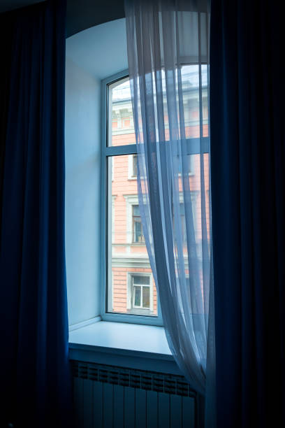 istock A window with blue curtains and a beautifully falling tulle. 2119496379