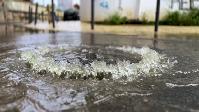 On a very rainy day, a sewer cover overflowing with water on a street in Portugal