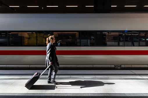 Germany, Berlin, March 26, 2024 - Blurred motion of woman walking in front of passenger train, Berlin Moabit