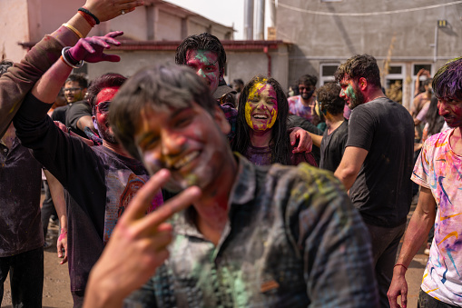 Uzbekistan, Samarkand, March 25, 2024: A man is posing for a picture with his hands on his hips and a woman is smiling at the camera. Scene is joyful and celebratory, as the group of people are likely participating in a festival or a party, Holi.