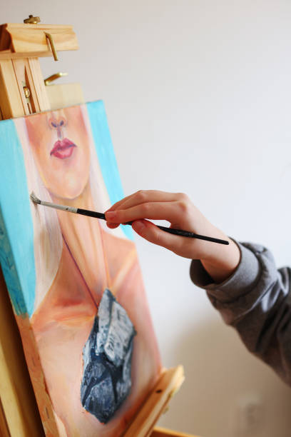 the artist's hand draws a picture that stands on an easel